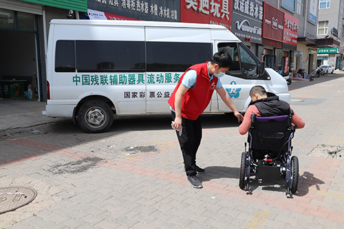 图为辅具工程师在指导残疾人操作电动轮椅