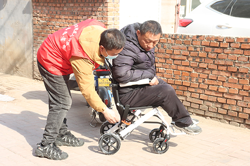 图为志愿者为肢体残疾人适配轮椅